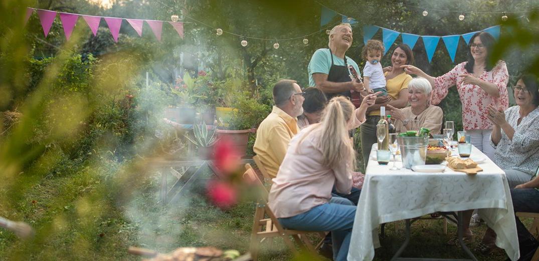 A family gathers for an outdoor meal accompanied by guitar music.